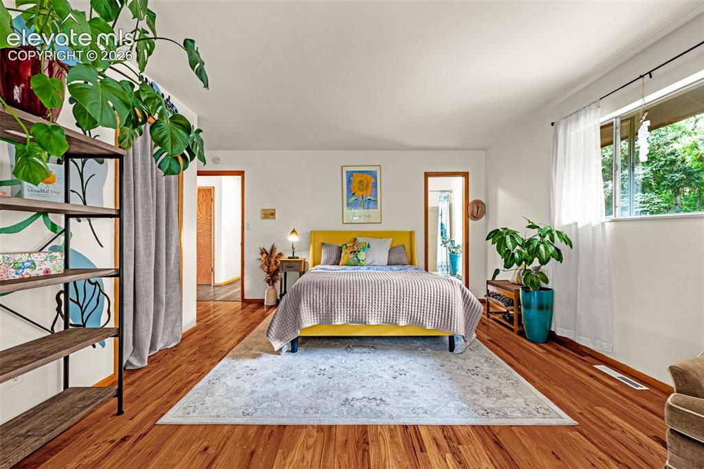Image 16 of 38: Spacious room with wood-finish flooring, white walls, and a large window