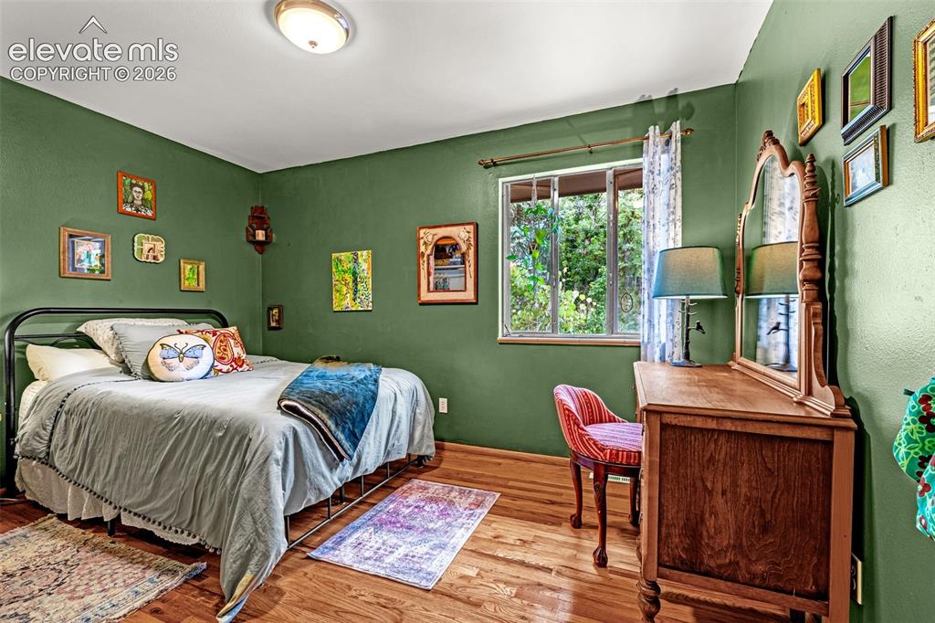 Image 21 of 38: Hardwood flooring throughout this room, featuring a window with exterior tr