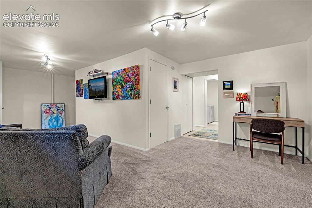 Image 27 of 38: Spacious carpeted room featuring track lighting and white walls