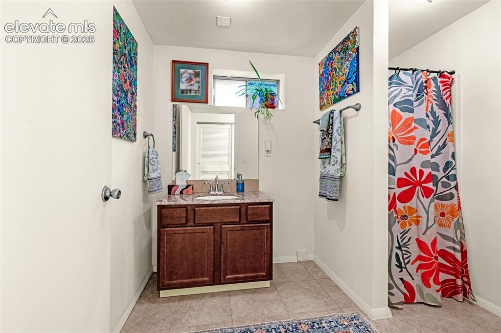 Image 31 of 38: Bathroom featuring a single vanity with a dark wood-finish cabinet and a po