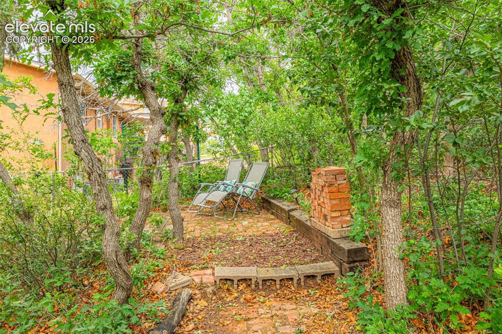Image 37 of 38: Heavily treed outdoor area featuring a brick patio with concrete block edgi