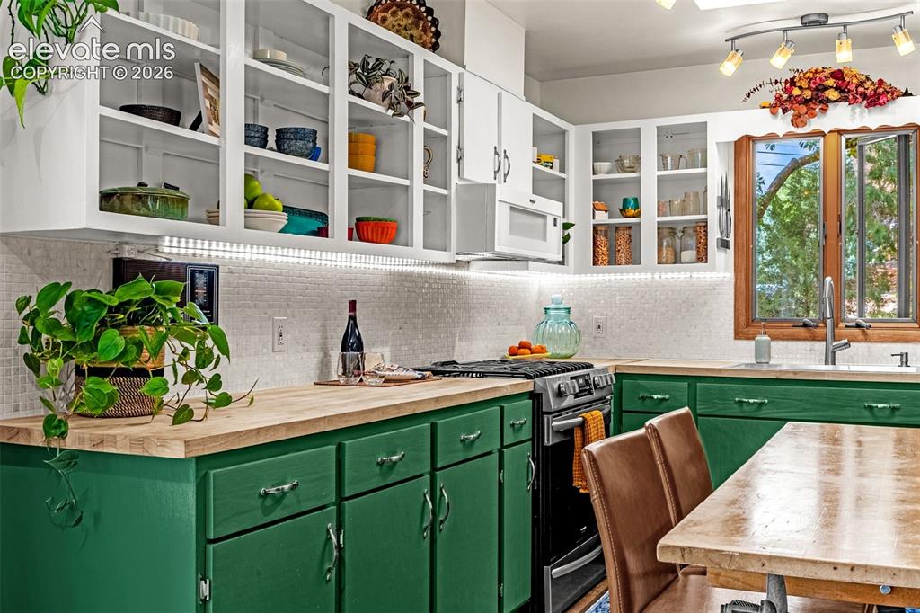 Image 4 of 38: Kitchen featuring white upper cabinetry, green lower cabinetry, wood-finish