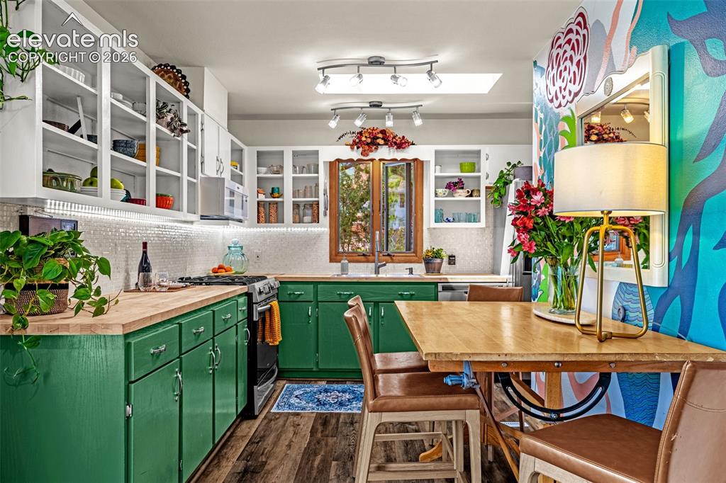 Image 5 of 38: Kitchen featuring green cabinetry, wood-finish countertops, and a full-heig