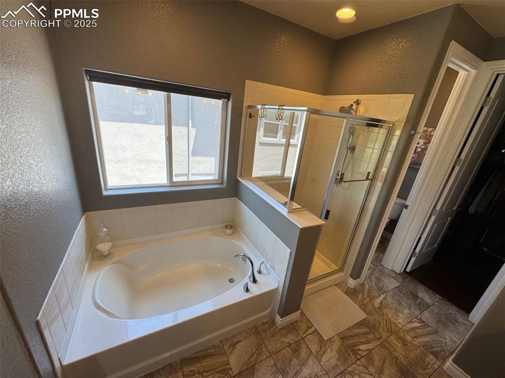 Image 14 of 40: Full bathroom with a textured wall, a garden tub, and a shower stall