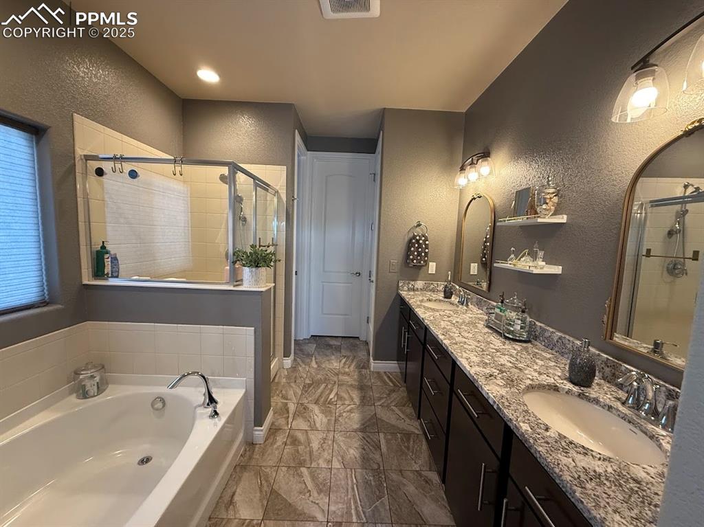 Image 15 of 40: Bathroom with a sink, a bath, a stall shower, and a textured wall