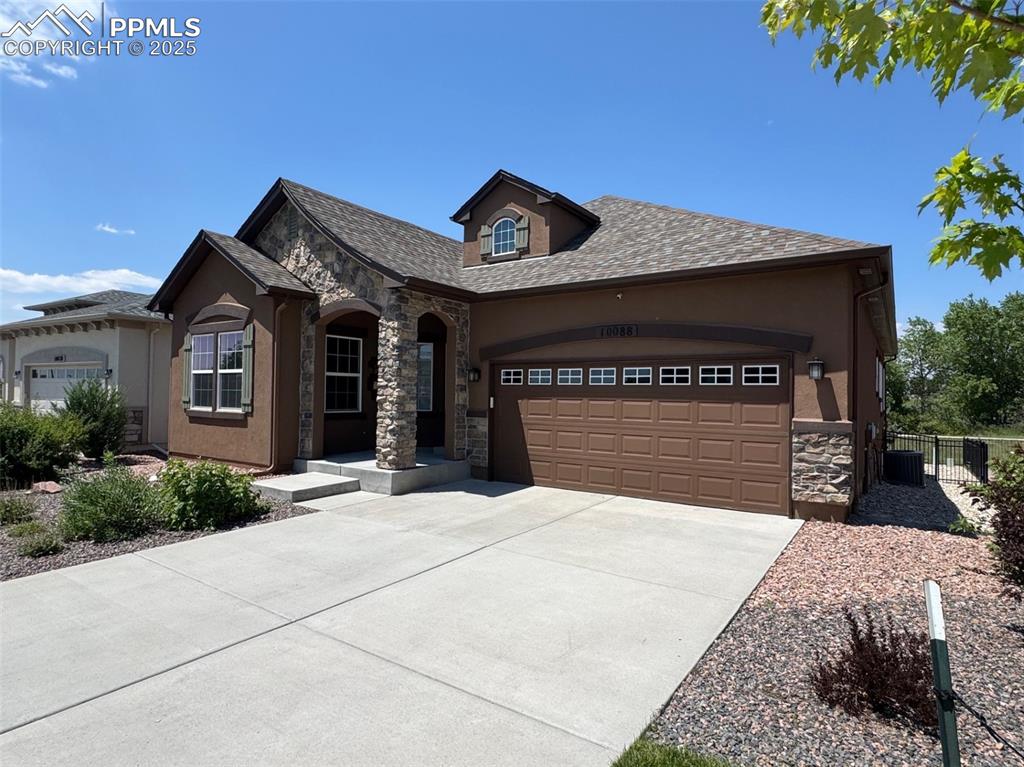Image 2 of 40: View of front of house with stone siding, concrete driveway, a garage, stuc