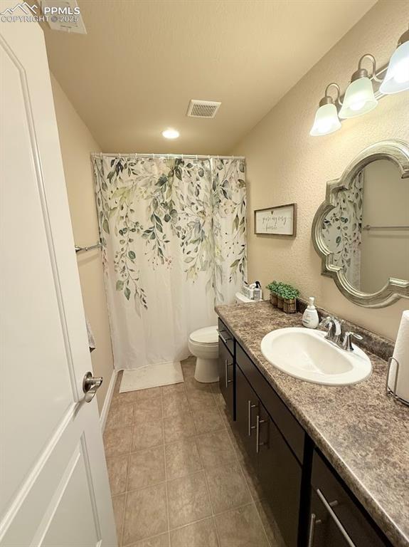 Image 22 of 40: Full bath in basement with vanity, a shower with curtain, visible vents, to