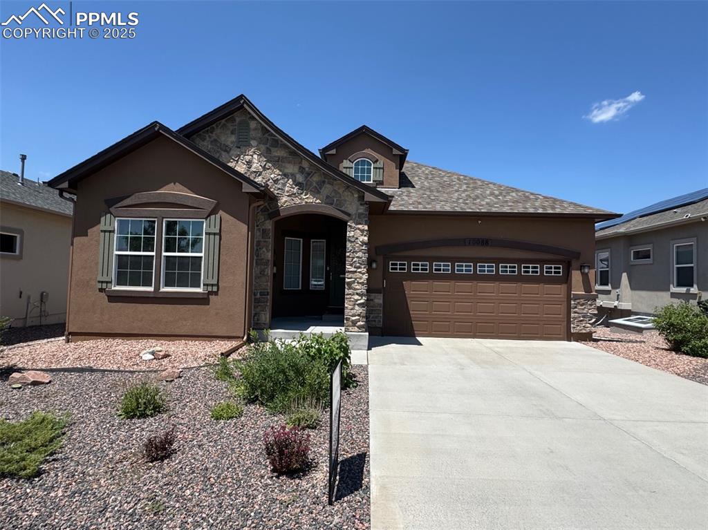 Image 3 of 40: View of front of property with stone siding, concrete driveway, stucco sidi