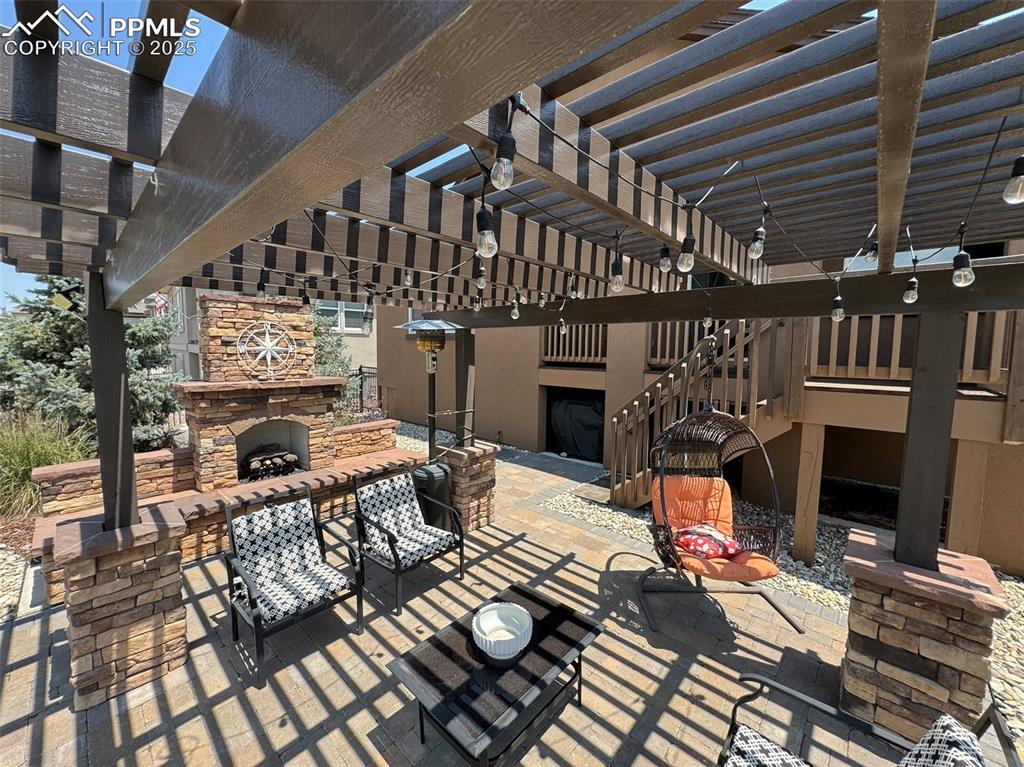 Image 32 of 40: View of patio with an outdoor stone fireplace and a pergola