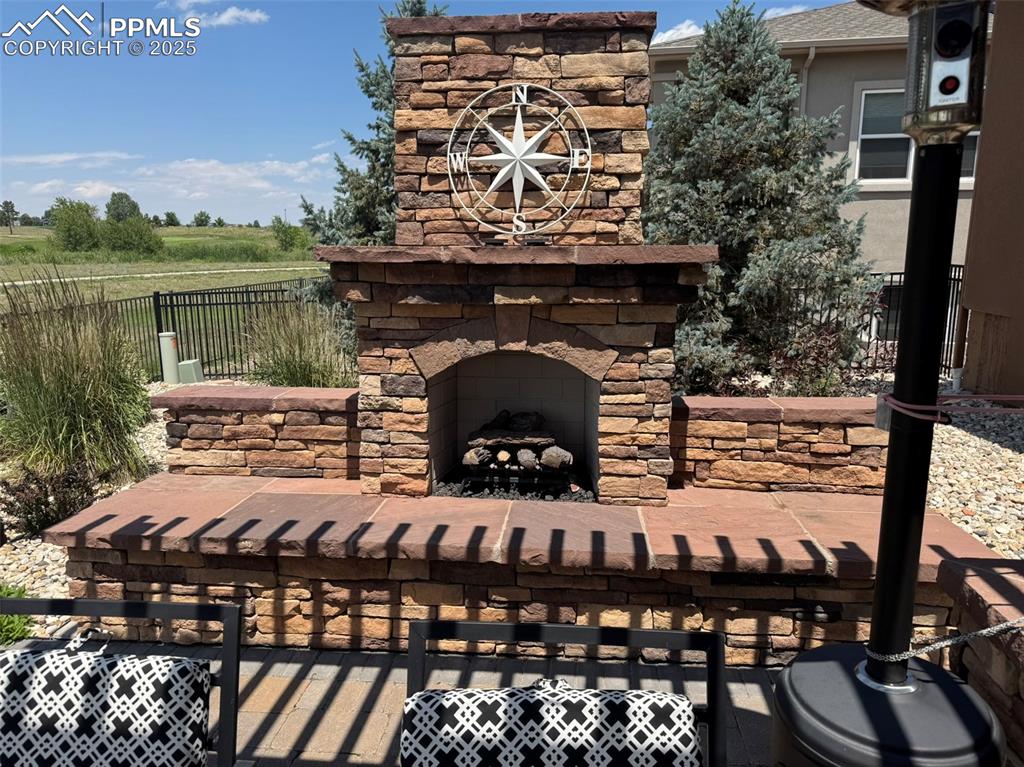 Image 33 of 40: View of patio featuring an outdoor stone fireplace and a view of rural / pa