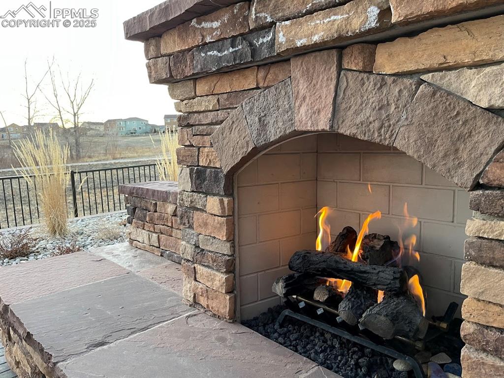 Image 35 of 40: Exterior details featuring fence and a lit fireplace
