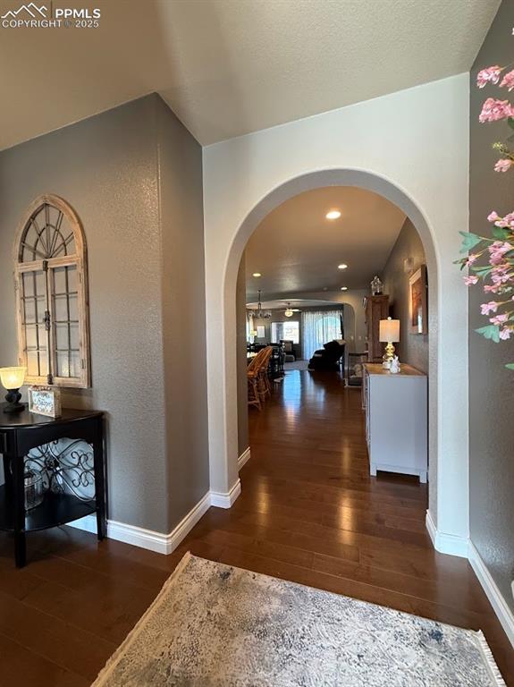 Image 4 of 40: Corridor with a textured wall, arched walkways, hardwood / wood-style floor