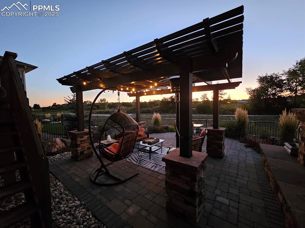 Image 40 of 40: Patio terrace at dusk featuring a pergola and fence
