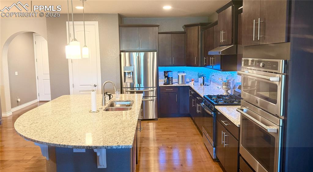 Image 8 of 40: Kitchen with appliances with stainless steel finishes, arched walkways, lig