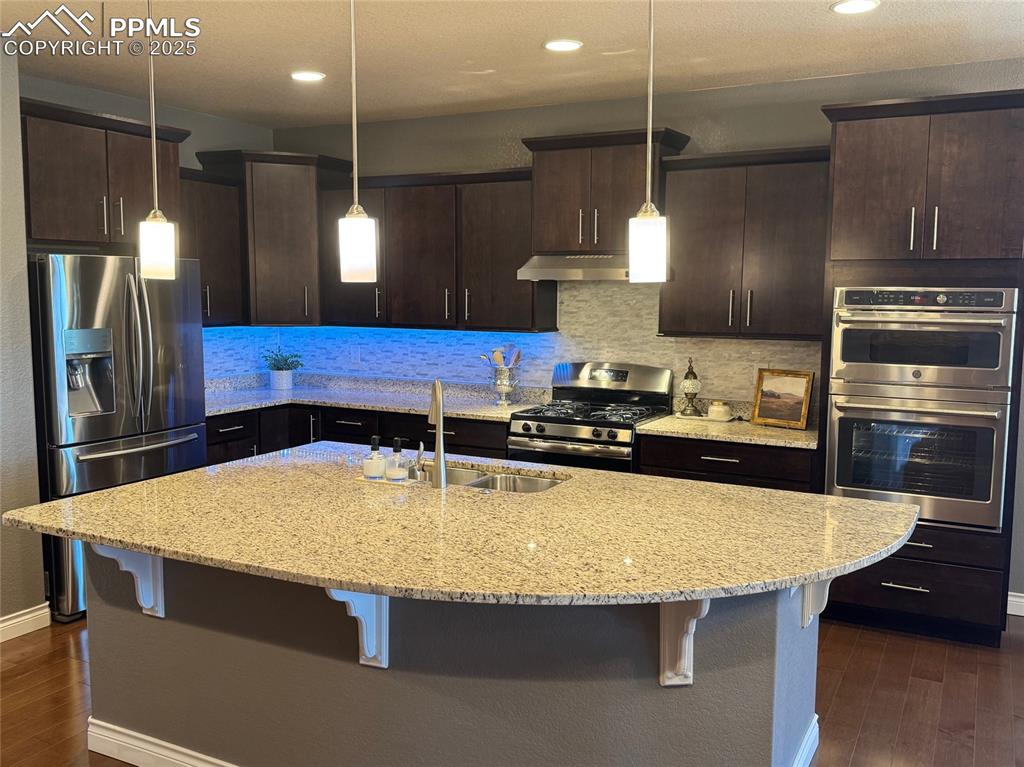 Image 9 of 40: Kitchen featuring appliances with stainless steel finishes, dark wood finis