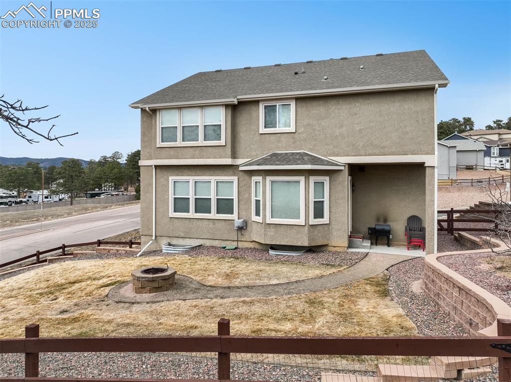 Image 45 of 50: Fenced back yard with landscaping, sprinklers, wood fire pit and patio acce