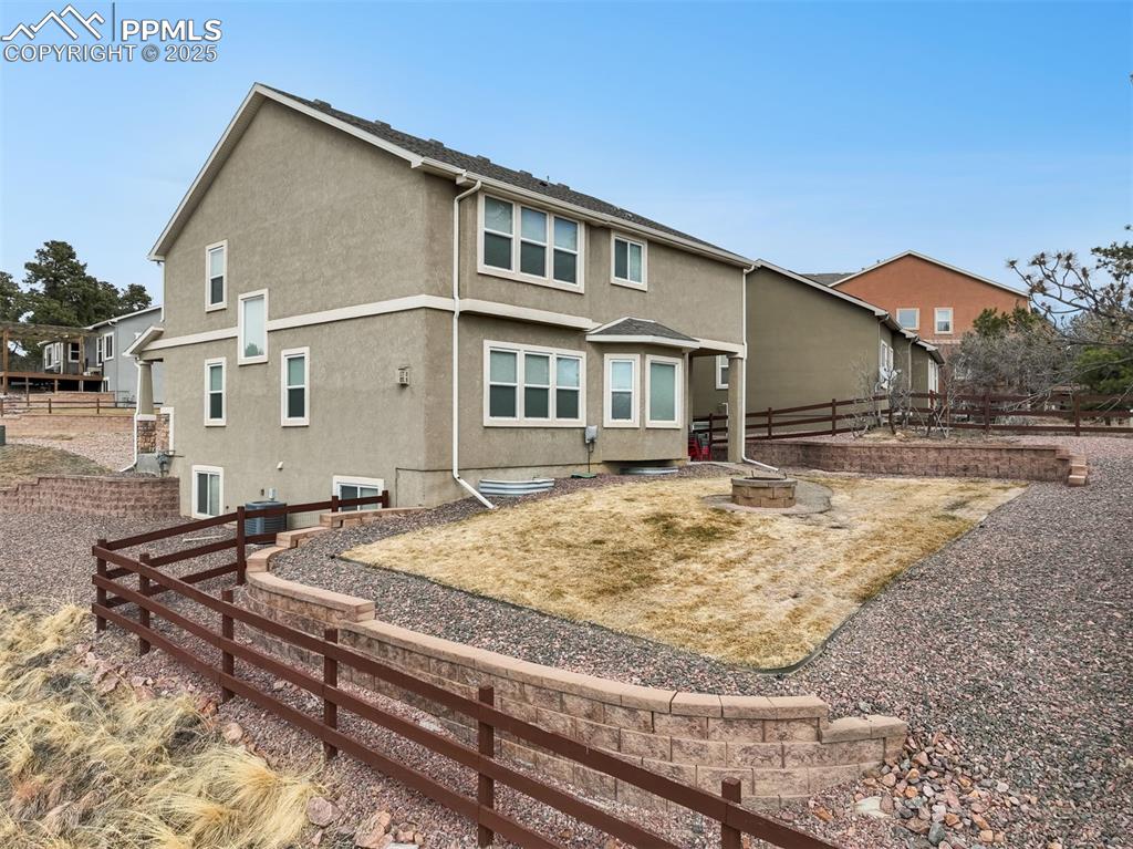 Image 47 of 50: Fenced back yard with landscaping, sprinklers, wood fire pit and patio acce