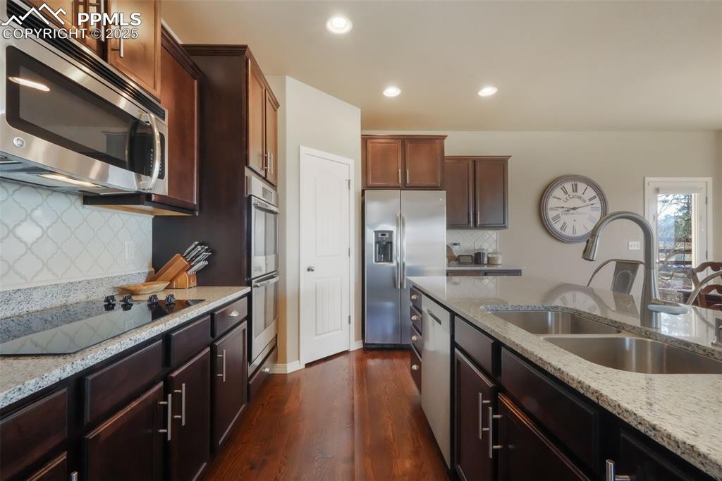 Image 7 of 50: Kitchen with stainless steel appliances, granite counters, double wall oven