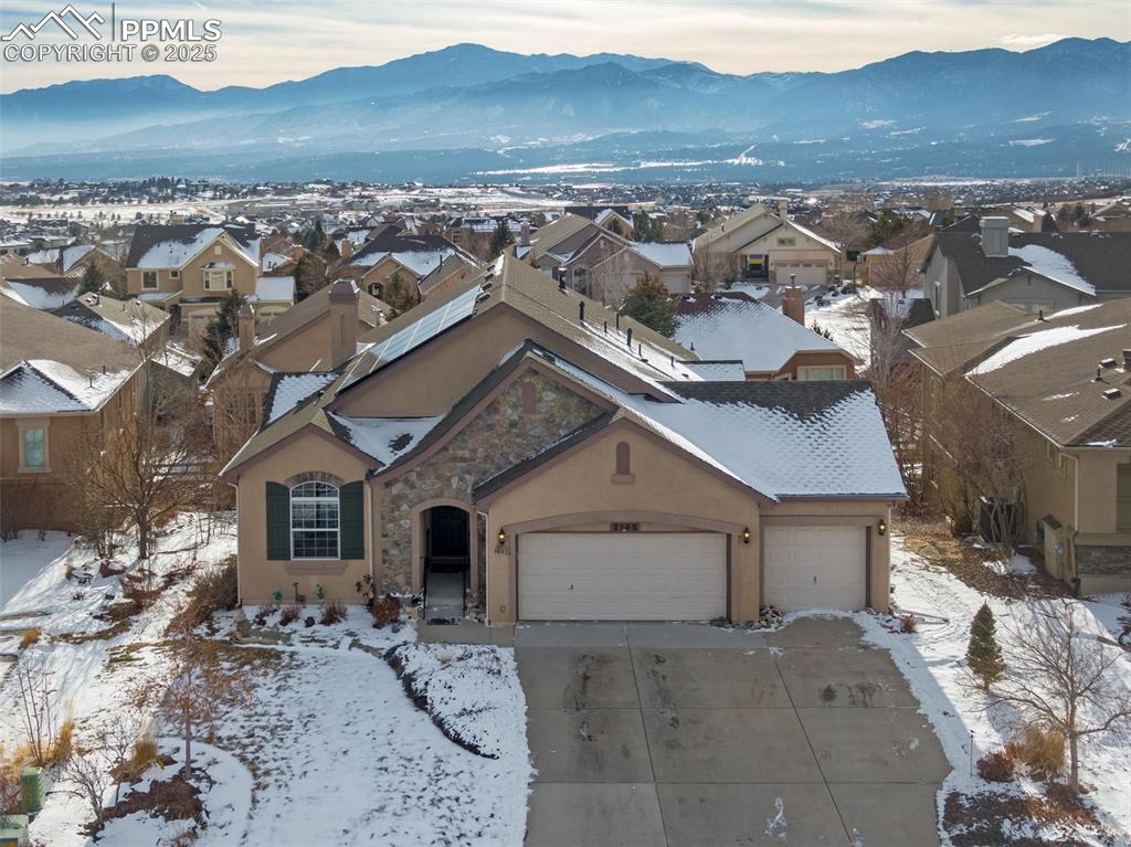 Image 4 of 47: View of front of house with an attached garage, stone siding, a mountain vi