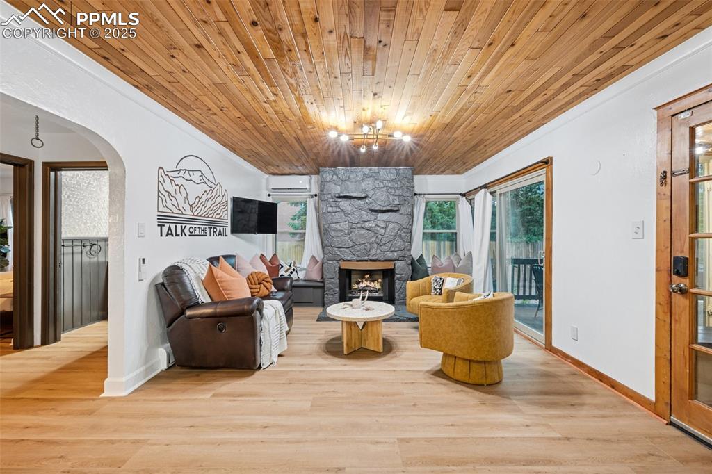 Image 11 of 48: Living room with arched walkways, wood ceiling, a stone fireplace, wood fin