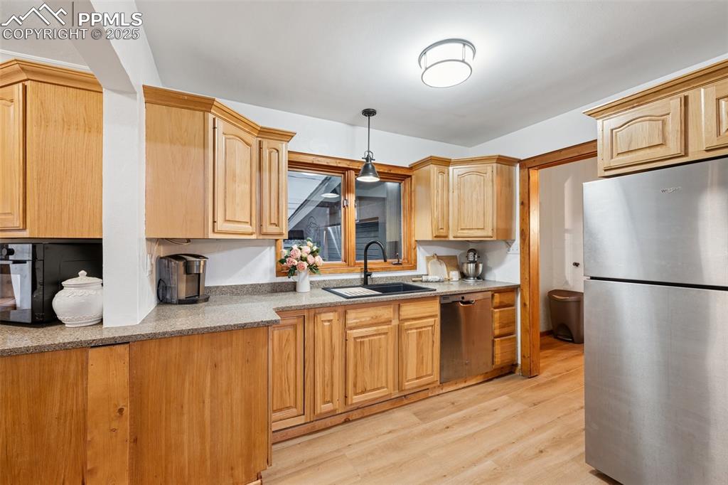 Image 13 of 48: Kitchen with stainless steel appliances, light wood-type flooring, decorati