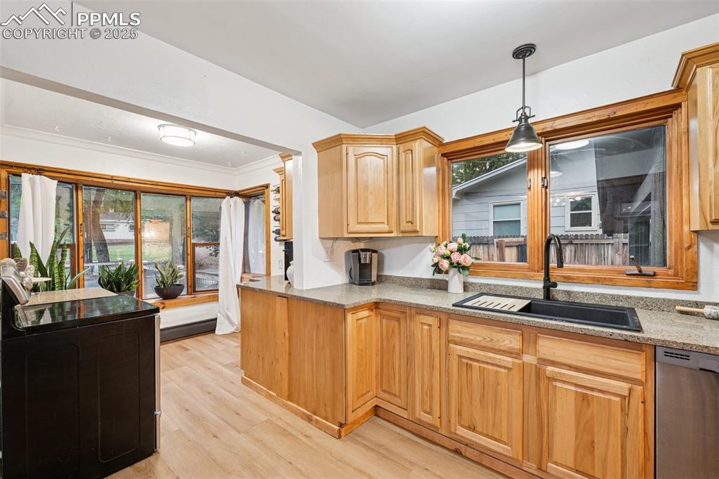 Image 14 of 48: Kitchen with stainless steel dishwasher, light stone counters, light wood-s