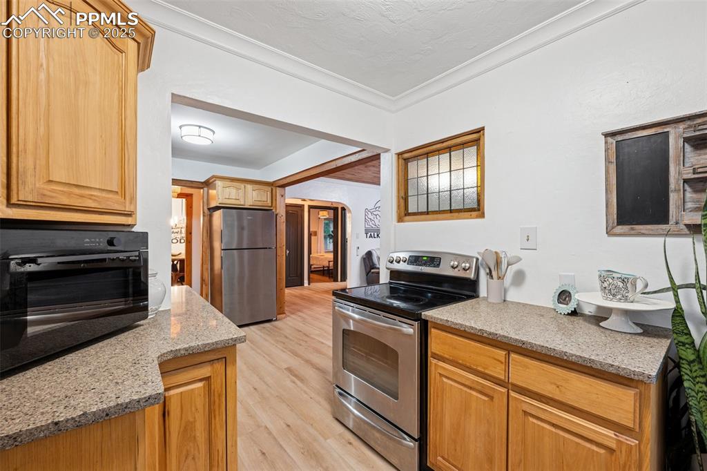 Image 15 of 48: Kitchen with appliances with stainless steel finishes, light wood-style flo