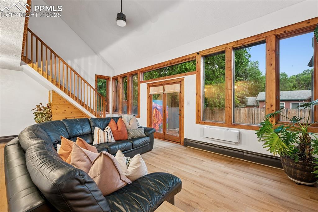 Image 18 of 48: Living room with healthy amount of natural light, stairway, lofted ceiling,