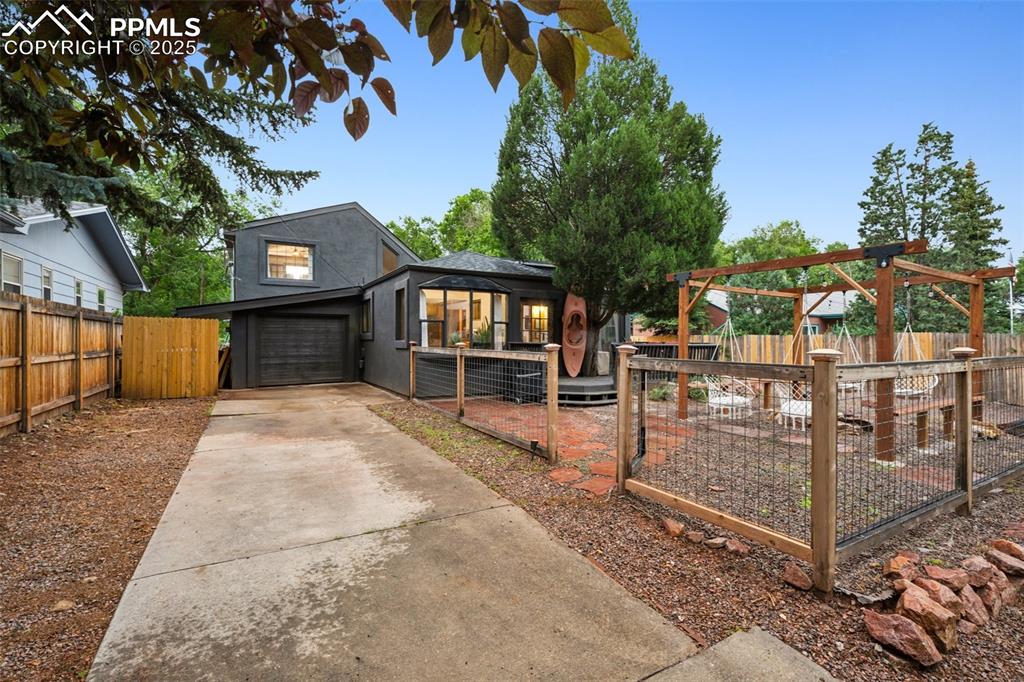 Image 2 of 48: View of front facade featuring driveway, a gate, a garage, and stucco sidin