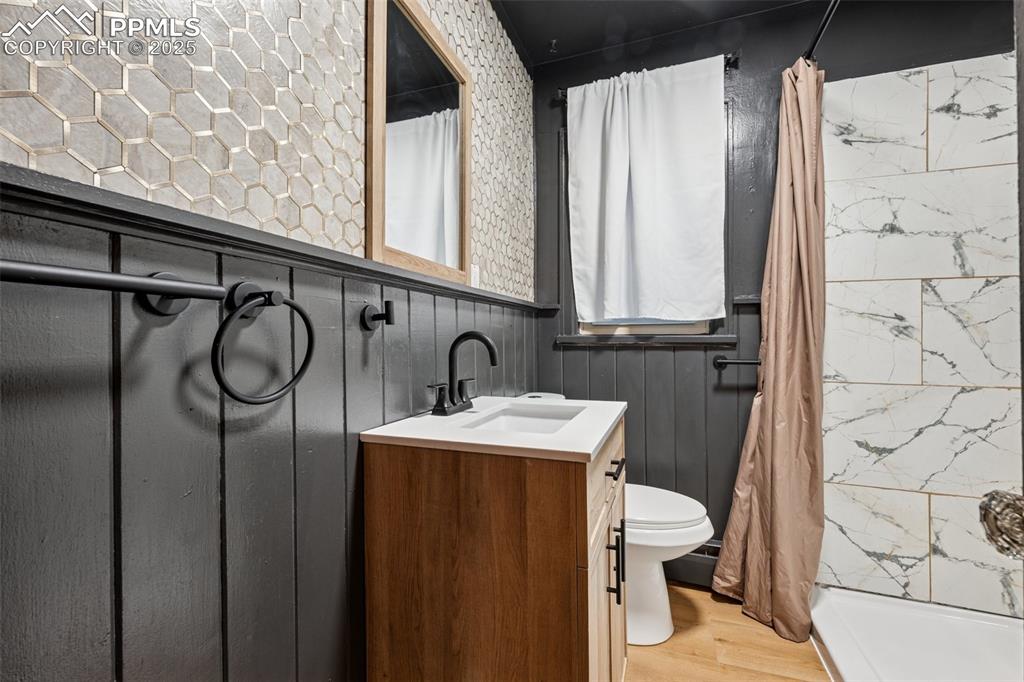 Image 22 of 48: Bathroom with wood finished floors, vanity, and curtained shower