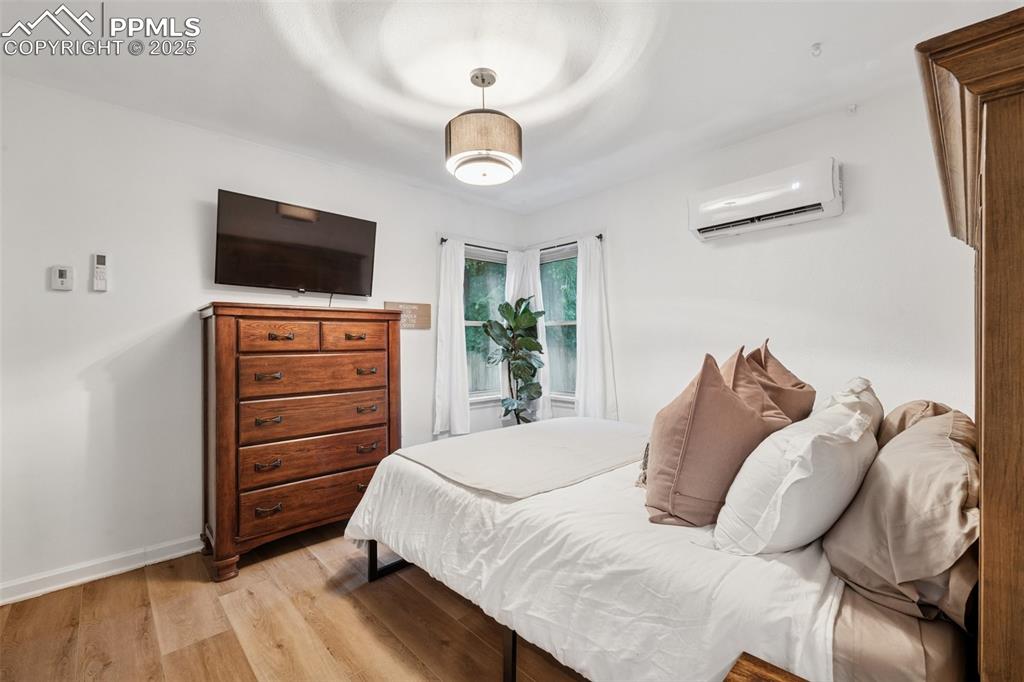 Image 23 of 48: Bedroom with light wood-style flooring and a wall unit AC