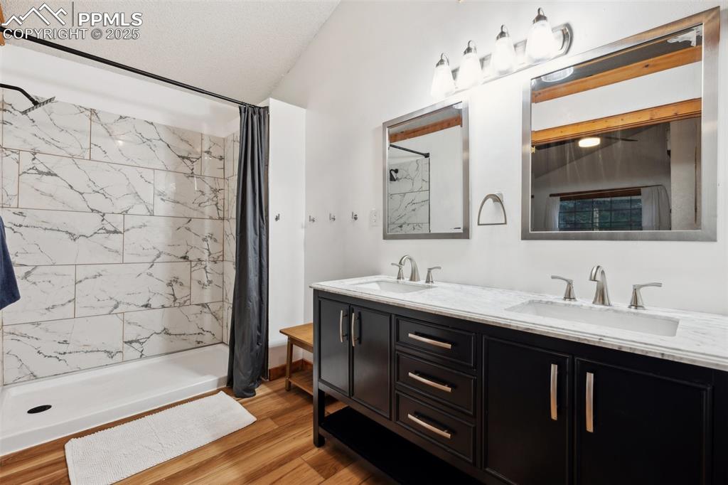 Image 25 of 48: Full bathroom with double vanity, a shower with shower curtain, and wood fi
