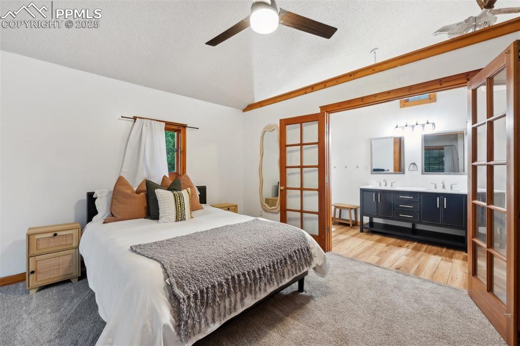 Image 26 of 48: Bedroom featuring vaulted ceiling, ensuite bathroom, light wood-type floori