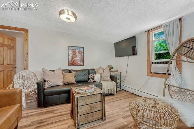 Image 31 of 48: STR portion: Living area featuring a textured ceiling, wood finished floors