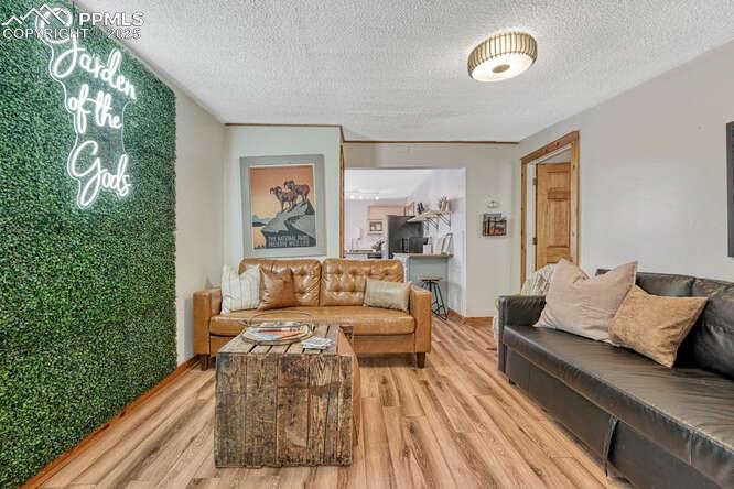 Image 32 of 48: STR portion: Living room with light wood finished floors and a textured cei