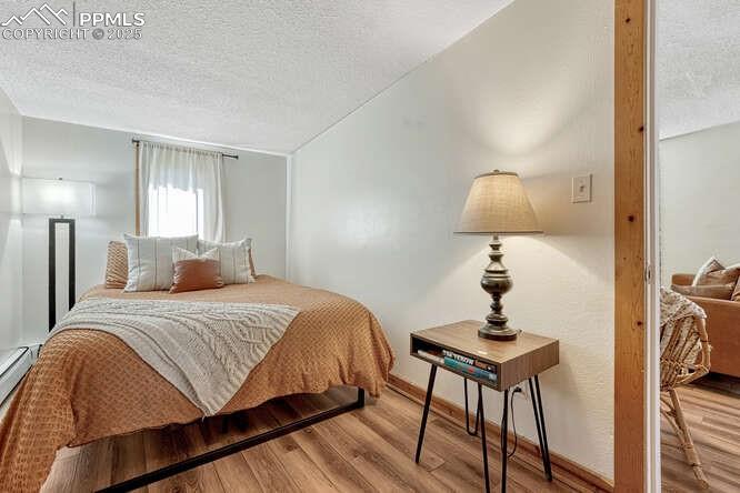 Image 42 of 48: STR portion: Bedroom featuring wood finished floors, a textured ceiling, an