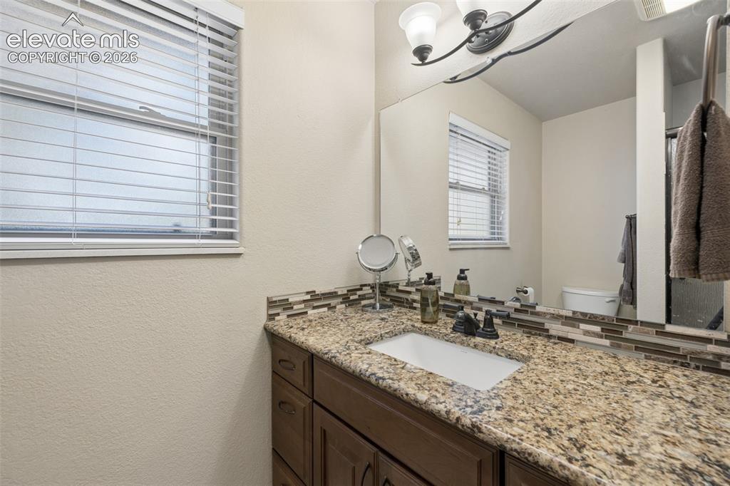 Image 18 of 36: Primary 3/4 bathroom with granite countertop and walk-in shower