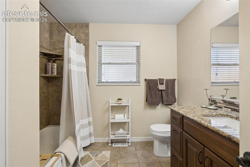 Image 21 of 36: Full guest bathroom on the main level with granite countertop