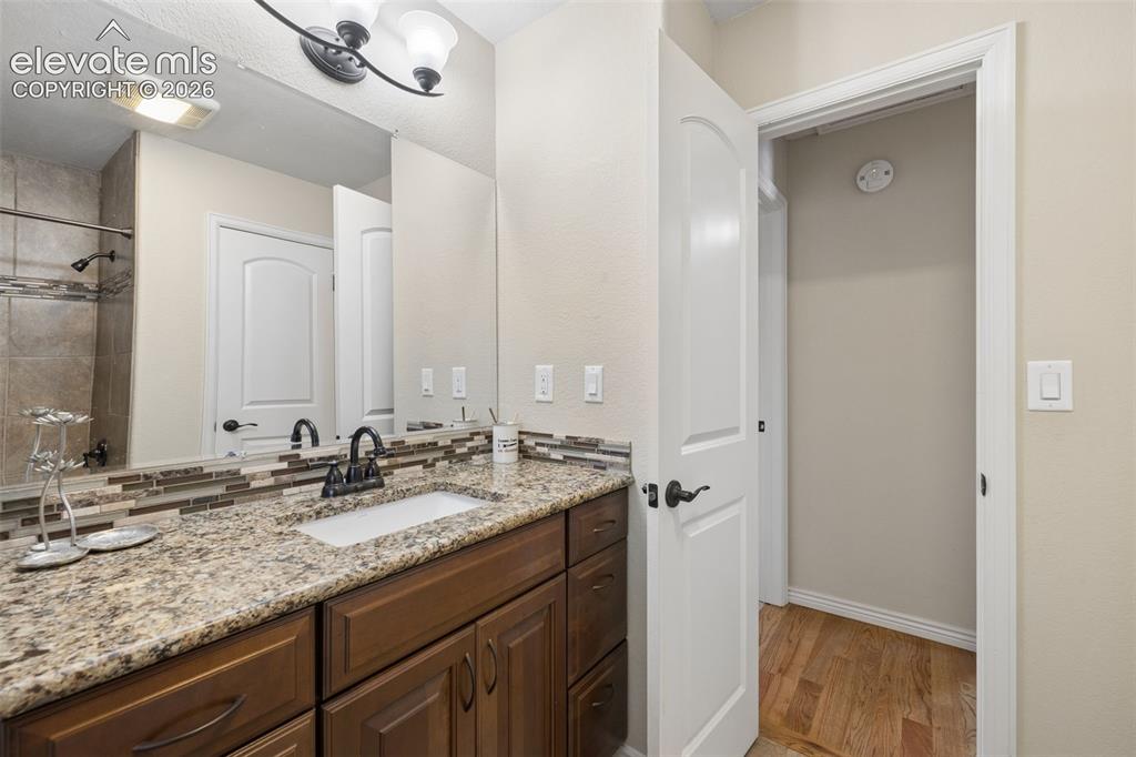 Image 22 of 36: Full guest bathroom on the main level with granite countertop