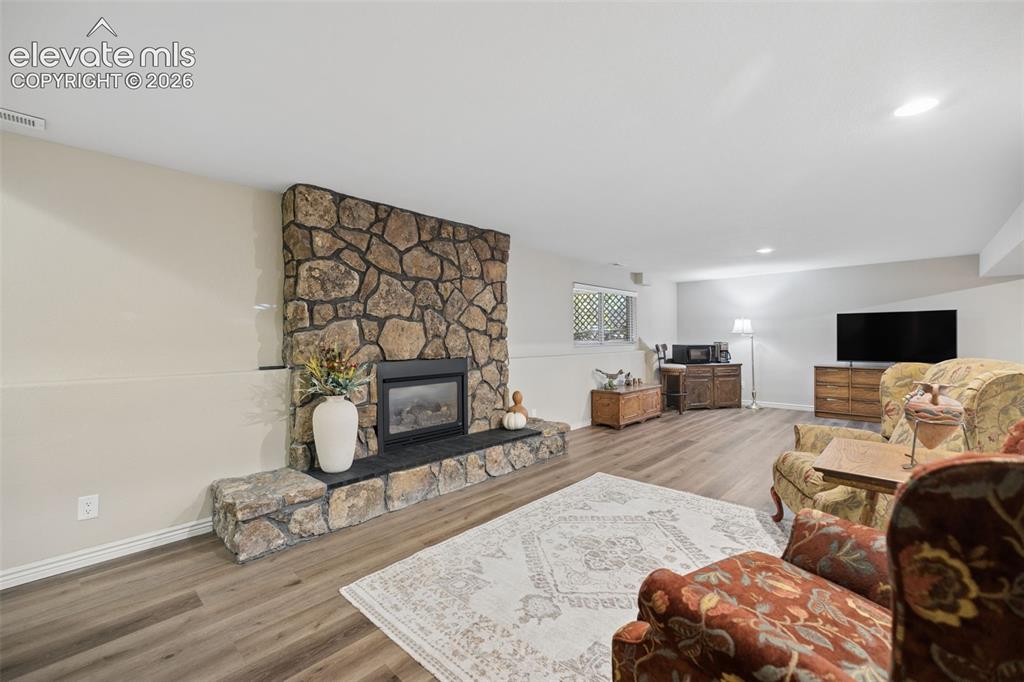 Image 24 of 36: Spacious basement flex room with gas fireplace with stone surround and LVP