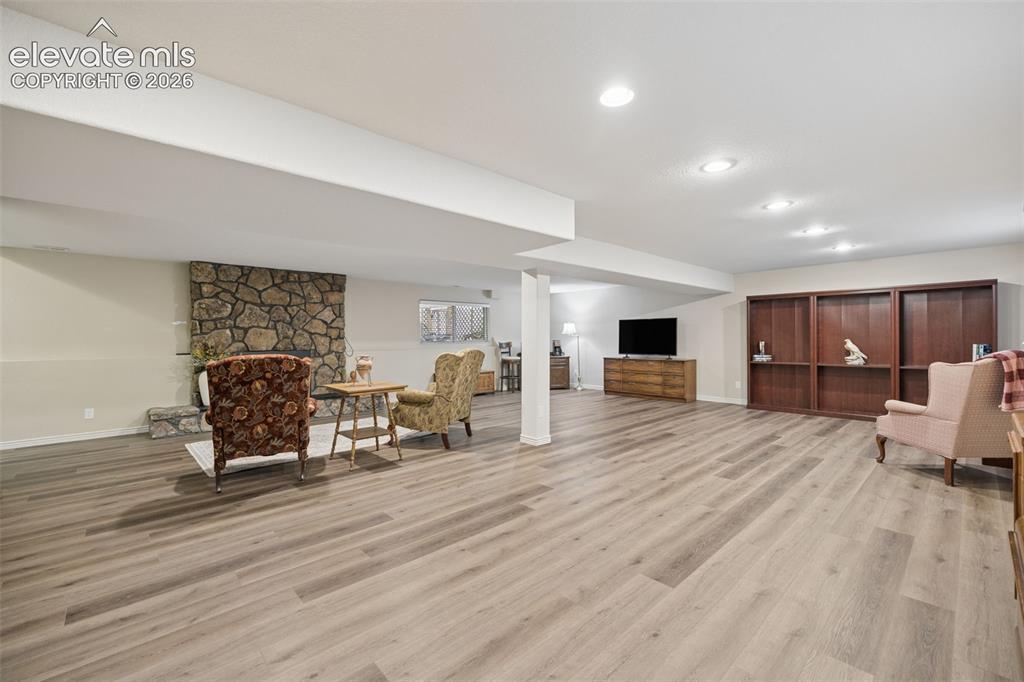 Image 25 of 36: Spacious basement flex room with gas fireplace with stone surround and LVP