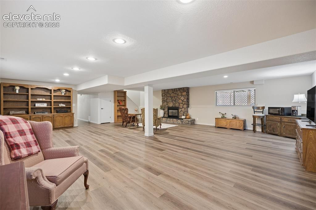 Image 26 of 36: Spacious basement flex room with gas fireplace with stone surround and LVP