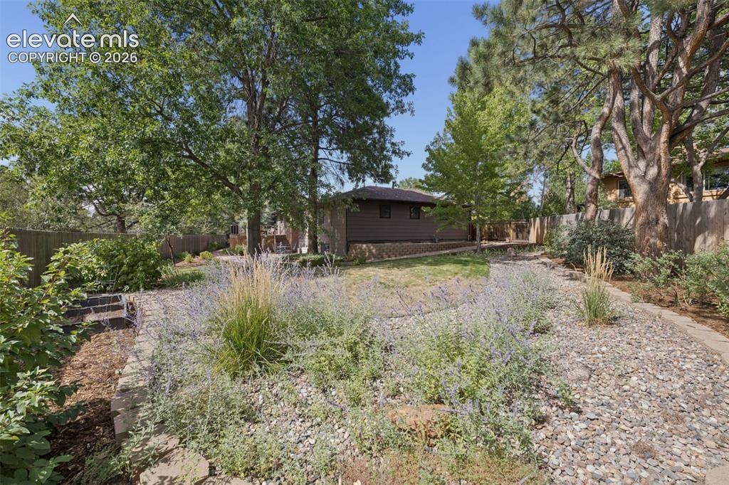 Image 31 of 36: Park-like backyard has room to garden and fencing for privacy amidst mature