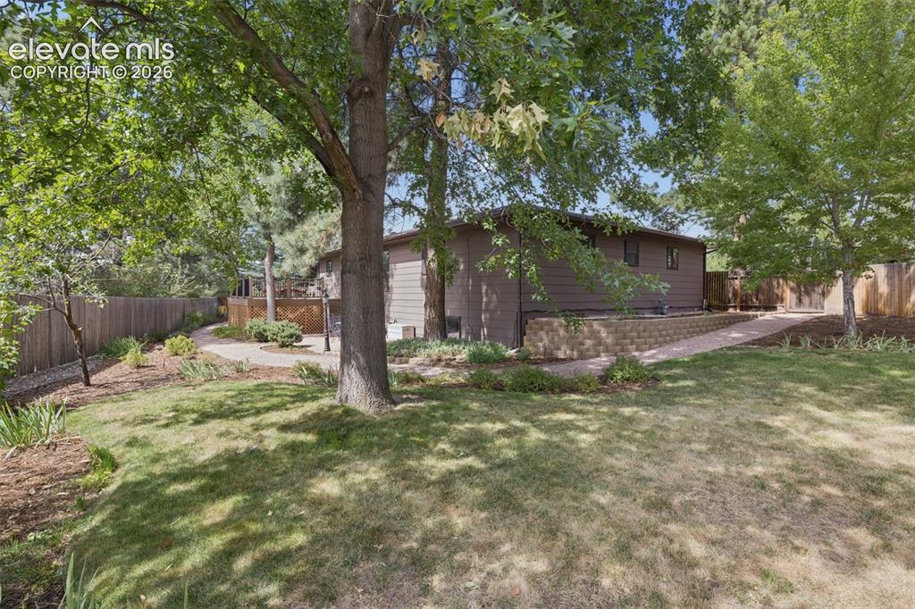 Image 33 of 36: Exterior landscape featuring tiered concrete block retaining walls, mature