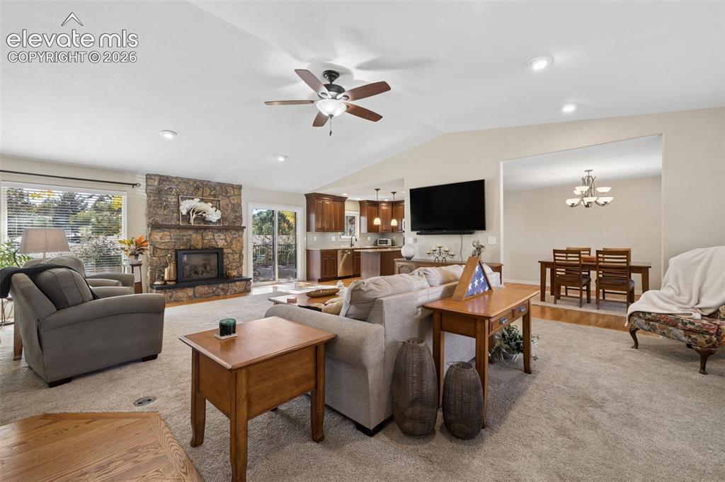 Image 4 of 36: Open-concept great room featuring vaulted ceilings and gas fireplace with s