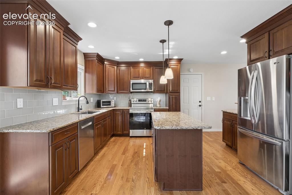 Image 9 of 36: Updated kitchen with island, granite counters and glass subway tile backspl