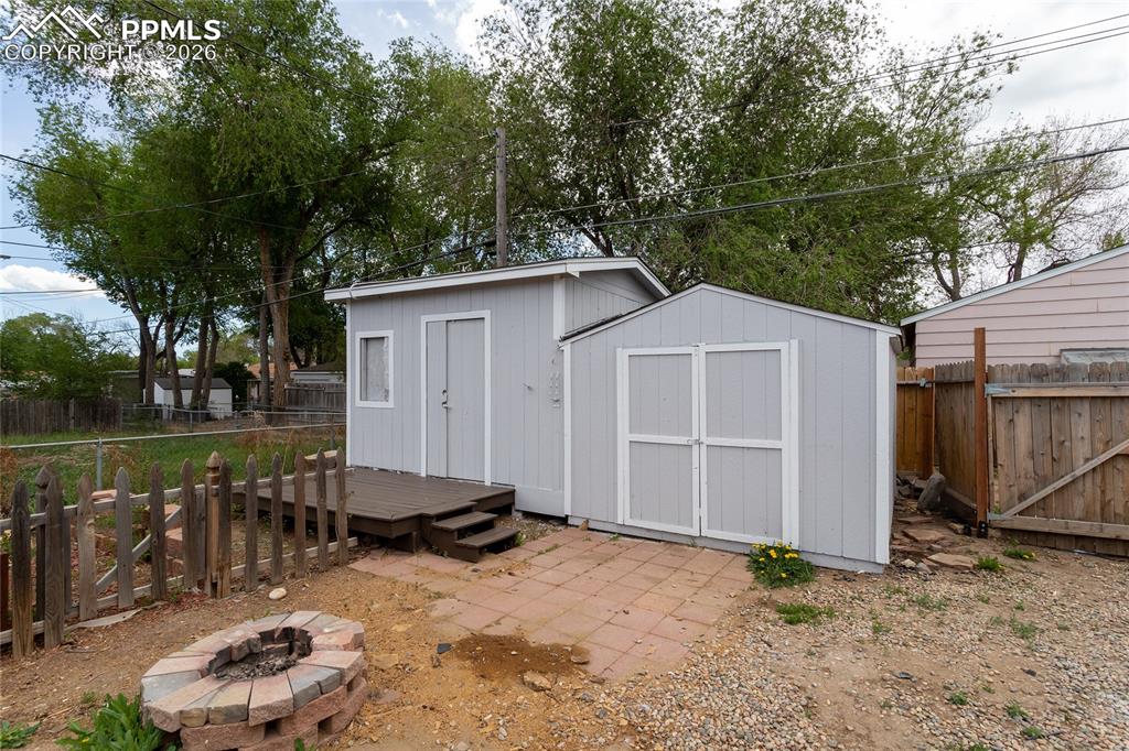 Image 33 of 48: Back yard firepit and double storage sheds