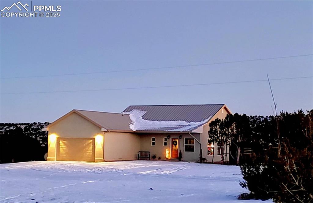 Caption: Single story home featuring an attached garage, stucco siding, and a metal roof