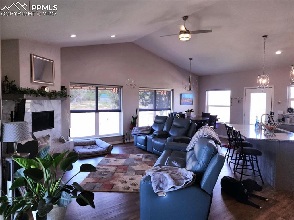 Image 11 of 47: Living area with wood finished floors, a ceiling fan, a chandelier, a high 