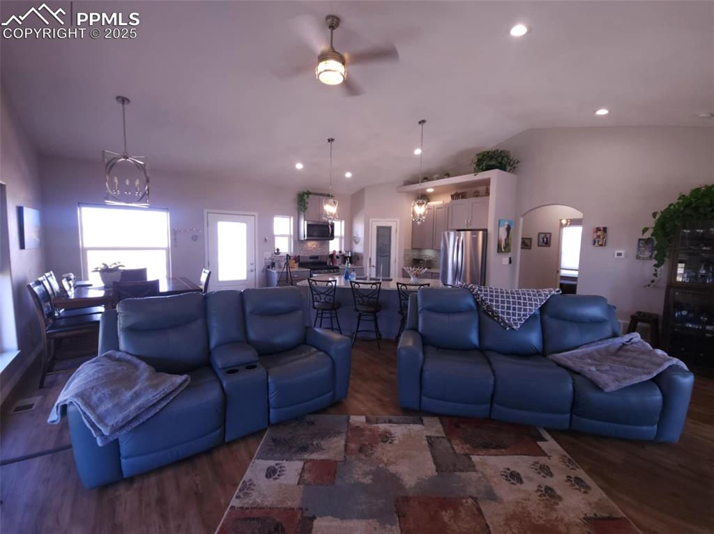 Image 12 of 47: Living area with a chandelier, a ceiling fan, vaulted ceiling, dark wood fi
